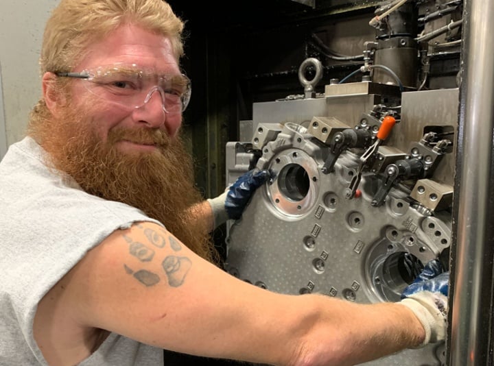 stecker-worker-pulling-part-out-of-cnc-mill-smiling 720w