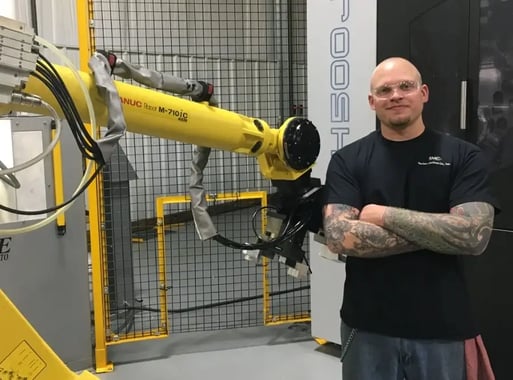 stecker-employee-with-arms-crossed-by-robotic-arm-opt